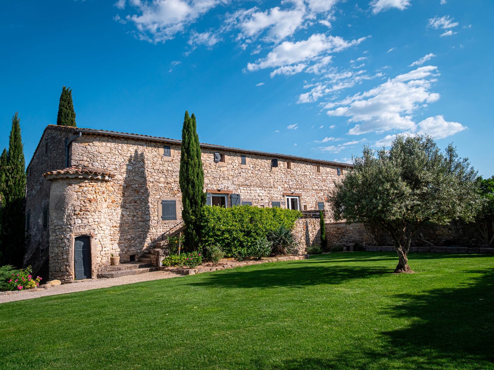 Un domaine en pierre entouré de cyprès sous le ciel de Provence